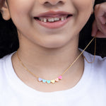 Tiny Jewels close-up of a child wearing a gold necklace with colorful heart-shaped pendants.