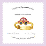 Tiny Jewels gold car-shaped ring with pink top on a white background with text about Tiny Jewels Rings.
