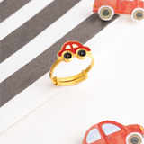 Tiny Jewels gold ring shaped like a car on a striped background with toy cars.