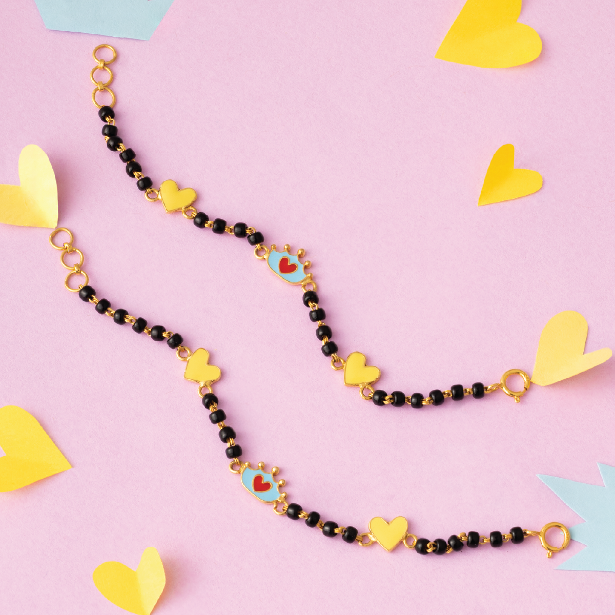 Tiny Jewels necklace with heart-shaped charms on a pink background with yellow heart shapes