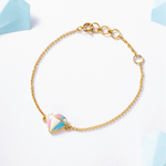 Tiny Jewels gold bracelet with a colorful triangle charm on a light background