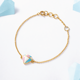 Tiny Jewels gold bracelet with a colorful triangle charm on a light background