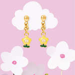 Tiny Jewels gold floral earrings with green leaves and pearls on a pink background with white flowers.