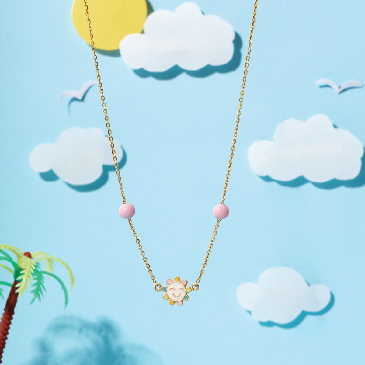 Tiny Jewels necklace with a bear pendant on a blue background with clouds and a palm tree