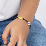 Tiny Jewels close-up of a child's hand wearing a bracelet with a blue and white flower charm, against a blurred background.