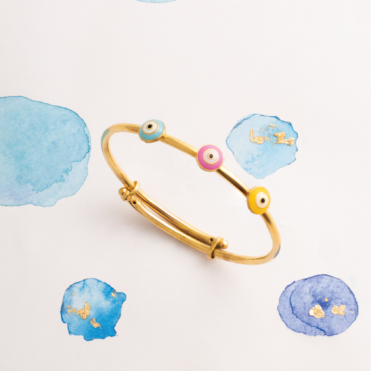 Tiny Jewels gold bracelet with colorful beads on a light background with watercolor textures