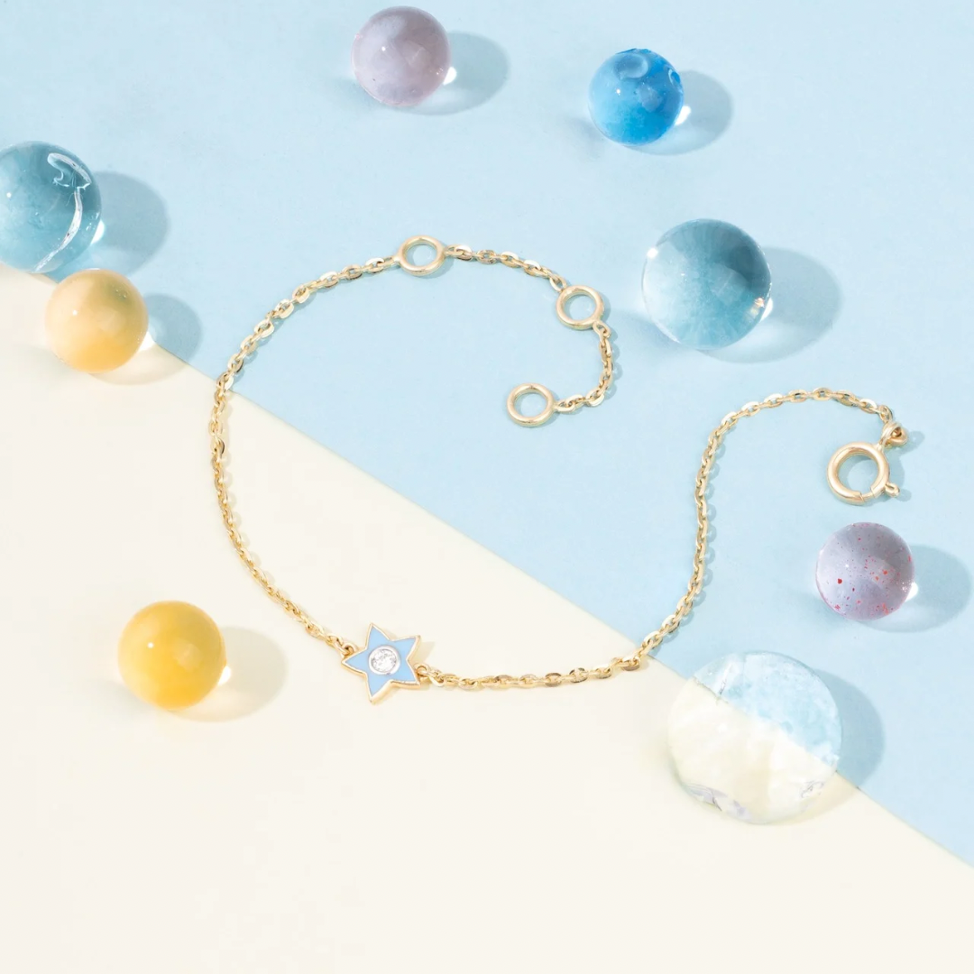 Tiny Jewels old bracelet with a star charm on a light blue and white background with colorful beads.