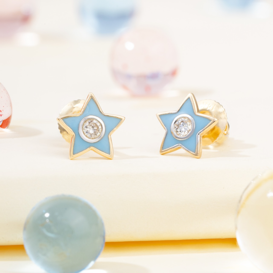 Tiny Jewels star-shaped earrings with blue enamel and gold accents on a soft background