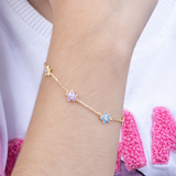 Tiny Jewels gold bracelet with star-shaped charms on a wrist against a white background