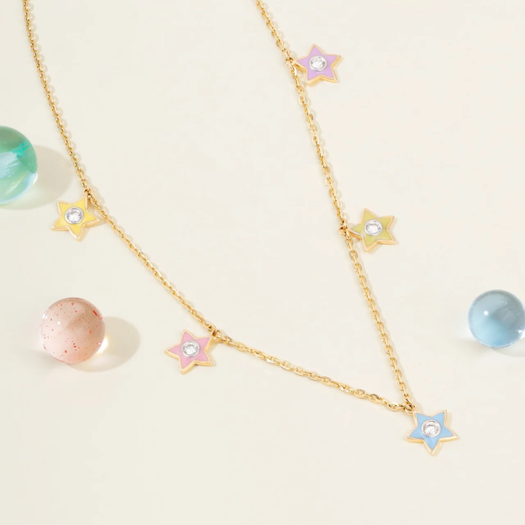 Tiny Jewels gold necklace with star-shaped pendants on a light background