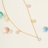 Tiny Jewels gold necklace with star-shaped pendants on a light background
