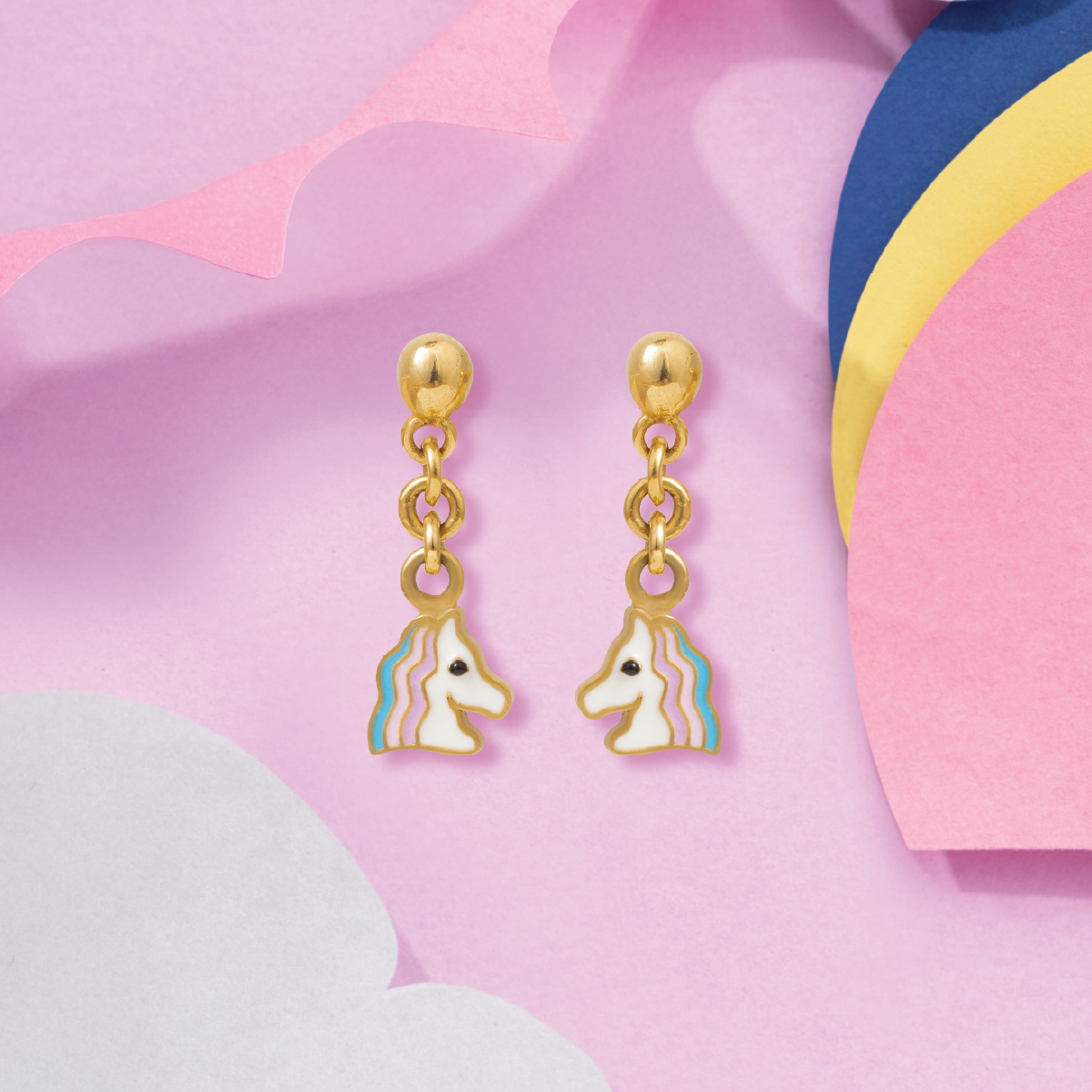 Tiny Jewels gold earrings with unicorn charms on a colorful abstract background