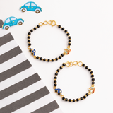 Tiny Jewels black beaded bracelets with gold accents and blue car charms on a white background with striped pattern.
